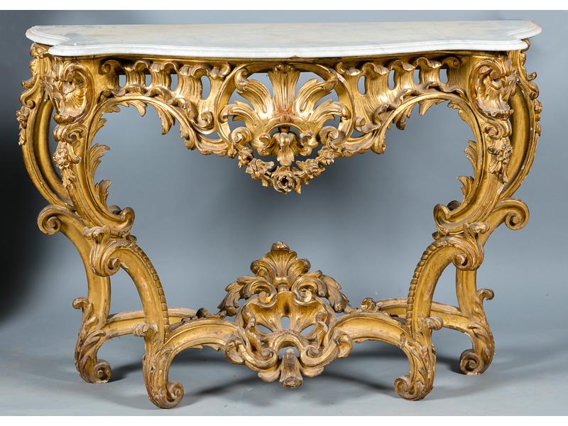 Importante console de style Louis XV à  toutes faces galbées, en bois sculpté, ajouré et doré. Plateau de marbre blanc reposant sur quatre pieds cambrés reliés par une entretoise. Riche décor de rocailles et coquilles. Epoque Napoléon III (écailles et sauts de dorure). Dim. 105x146x63 cm.  Provenanc