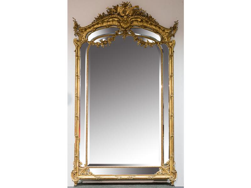 Important miroir biseauté dans un encadrement en bois et stuc doré à riche décor rocaille.  Fronton orné d'attributs musicaux et guirlandes de roses.  Epoque Napoléon III.  Dim.: 280x158 cm. (assorti au miroir précédent) (usures)
