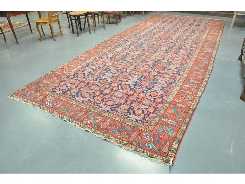 PERSE : Important tapis de passage en laine au point noué à décor de motifs géométriques rouges et bleus, bordures rouge et ivoire.  Dim.: 210x500 cm.
