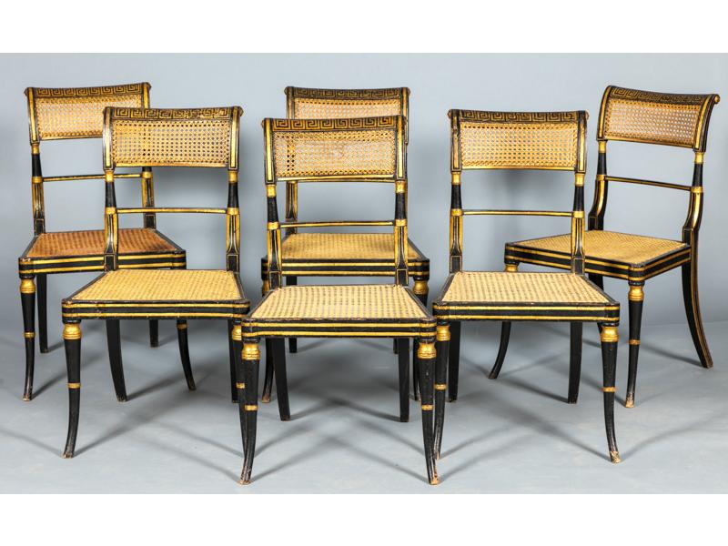 Suite de six chaises de style anglais en bois laqué noir et doré.  Les dossiers légèrement renversés, peints de frises à la grecque.  Dossiers et assises cannés.  Epoque XIXe siècle.
