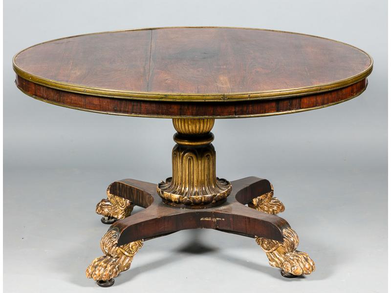 Table de salle à manger anglaise à plateau circulaire basculant en palissandre et placage de palissandre, à bord surligné d'une lingotière en laiton, reposant sur un fût palmiforme quadripode sculpté de griffes de lion.  Piètement en partie doré.  Epoque fin XIXe siècle.  Hauteur : 75 cm.  Diamètre