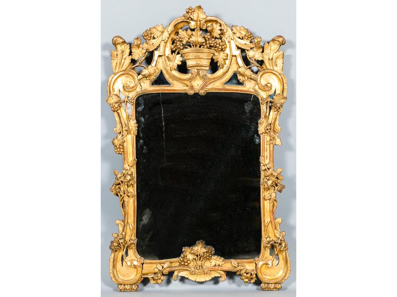 Miroir provençal dans un encadrement en bois doré, sculpté et ajouré à décor d'une coupe de fruits dans un cartouche, feuilles d'acanthe et pampres de vigne.  Milieu XVIIIe siècle.  Dim.: 105x67 cm.