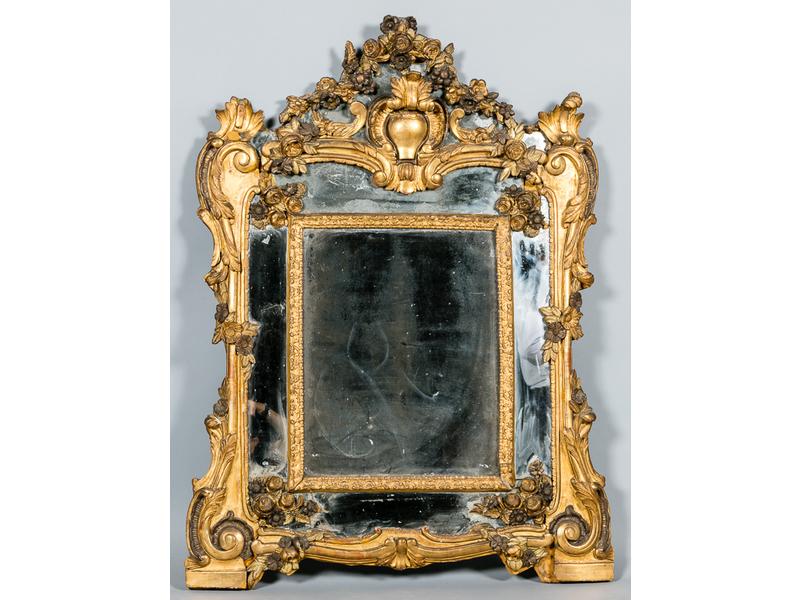 Miroir à parcloses en bois richement sculpté et doré à décor de guirlandes de fleurs, rocailles et feuillages (reprises à la dorure et petits accidents). Epoque XVIII° siècle. Dim.: 120x87cm