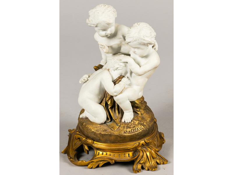 D'après MACHAULT : Groupe en biscuit et bronze représentant trois putti reposant sur un socle de style rocaille. Epoque XIXe siècle.  Hauteur : 22 cm. (petits accidents aux doigts)