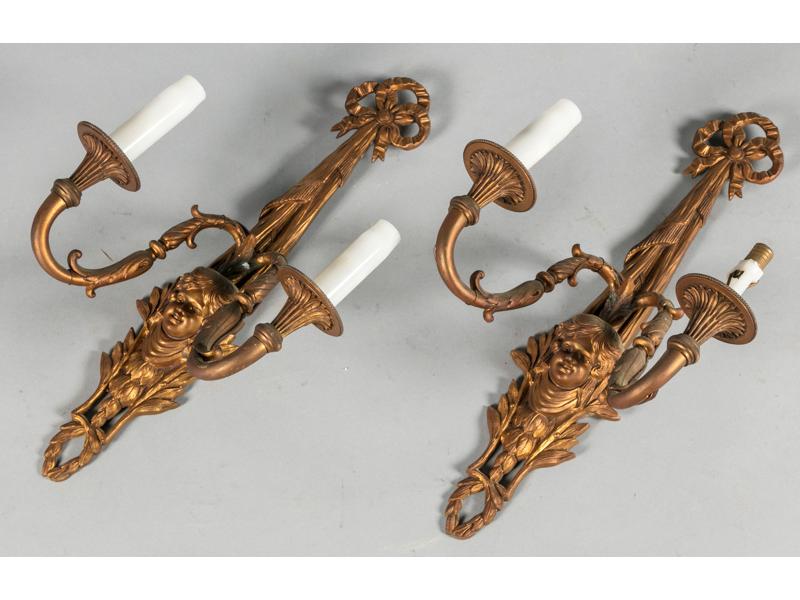 Paire d'appliques en bronze de style Louis XVI éclairant à deux bras de lumière ornés d'un mascaron et feuillages.  Epoque fin XIXe siècle.  Hauteur : 43 cm.