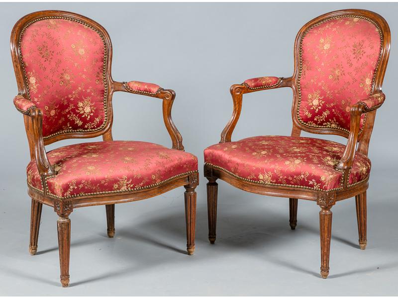 Paire de fauteuils cabriolets en noyer naturel mouluré, supports d'accotoirs en coup de fouet, piètement fuselé et cannelé.  Epoque Transition Louis XV-Louis XVI.