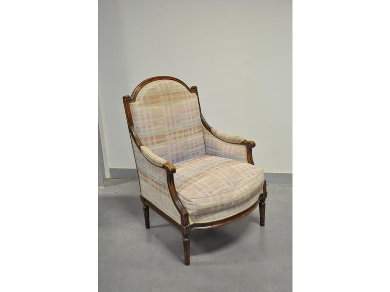 Bergère Louis XVI en bois naturel, dossier plat chapeau de gendarme, consoles d'accotoir et piètement fuselés et rudentés. En partie restaurée. Tissu moderne.