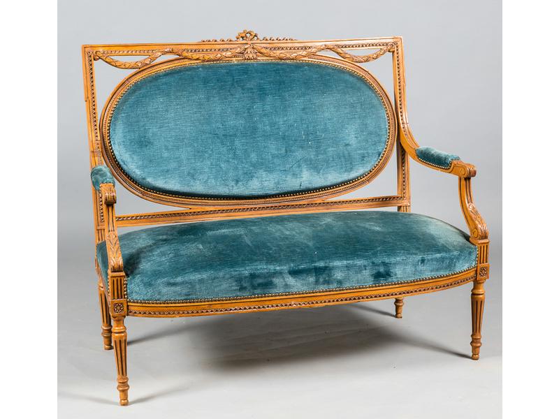 Petit canapé de style Louis XVI en bois laqué. Dossier de forme rectangulaire ajouré et sculpté d'une guirlande rubannée et reposant sur quatre pieds fuselés et cannelés. Long.: 110cm