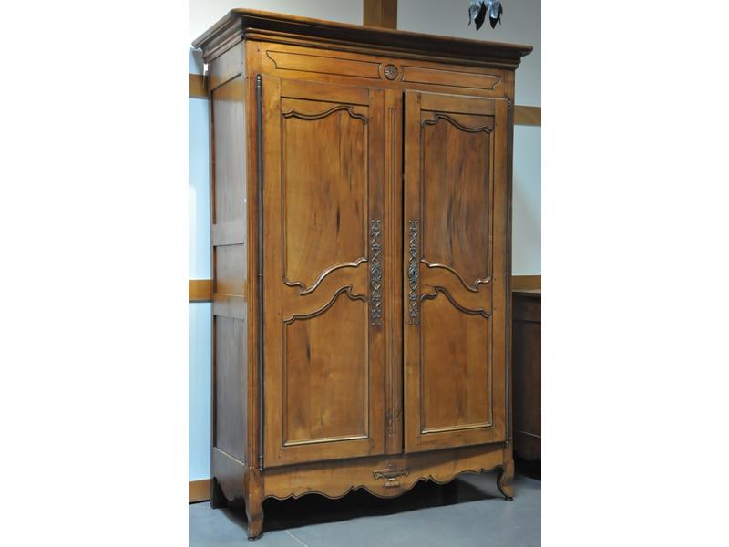 Petite armoire en merisier ouvrant par deux portes moulurées à faux dormant cannelé.  Corniche droite.  Linteau et traverse sculptés d'une rosace et urne.  Epoque XIXe siècle.  Dim.: 222x148x62 cm.