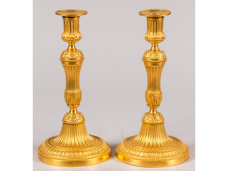 Paire de chandeliers en bronze doré à décor ciselé de cannelures, raies de coeur et rang de perles.  Epoque Louis XVI.  Hauteur : 27 cm. (repercés pour l'électricité)