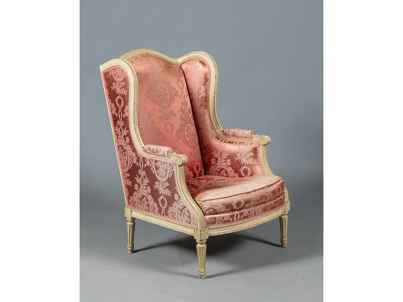 Grande bergère de style Louis XVI en bois mouluré et laqué blanc, dossier à oreilles, reposant sur quatre petits pieds fuselés et cannelés (usures à la laque).