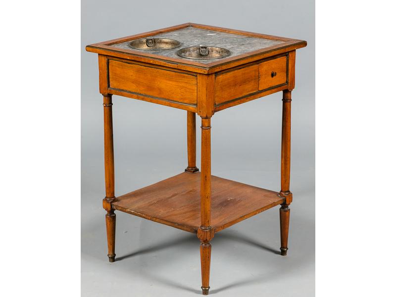 Petite table rafraichissoir en bois fruitier. Plateau de forme carrée en marbre gris veiné blanc à deux réservoirs en tôle, ouvrant par un petit tiroir latéral en ceinture. Epoque début XIXe siècle.  Dim.: 70x47x47 cm.