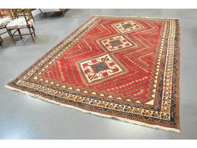 IRAN : Tapis en laine à fond rouge à décor central de trois médaillons en losange. Dim. 290 x 212 cm.