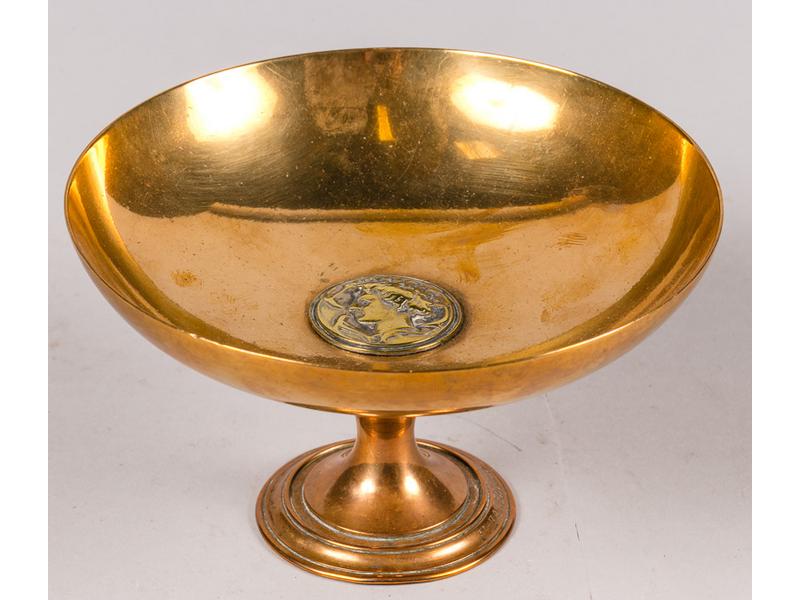 Coupelle circulaire en laiton, le centre du bassin orné d'un profil de femme à l'Antique reposant sur un petit piédouche.  XIXe siècle.  Hauteur : 9 cm.  Diamètre : 15 cm.