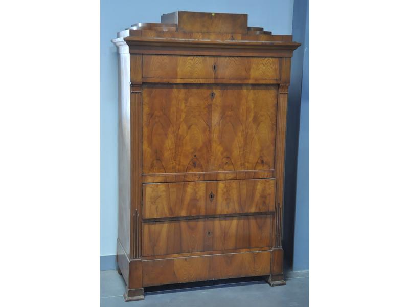 Secrétaire droit de forme architecturée en frêne et placage. Montants à pilastres cannelés, ouvrant par trois tiroirs et un abattant. Epoque Biedmermeïr. Dim.: 170x107x53 cm. (piètement à restaurer)