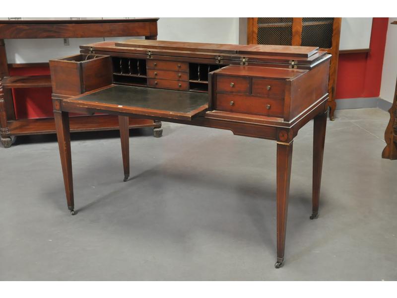 Bureau en acajou et placage d'acajou à décor marqueté de rosaces et filets de bois clair reposant sur un piètement gaine à roulettes.  Il ouvre par deux abattants découvrant un plateau coulissant gainé de cuir vert et des casiers et petits tiroirs.  Travail Anglais.  Dim.: 90x132x61 cm. (probablemen