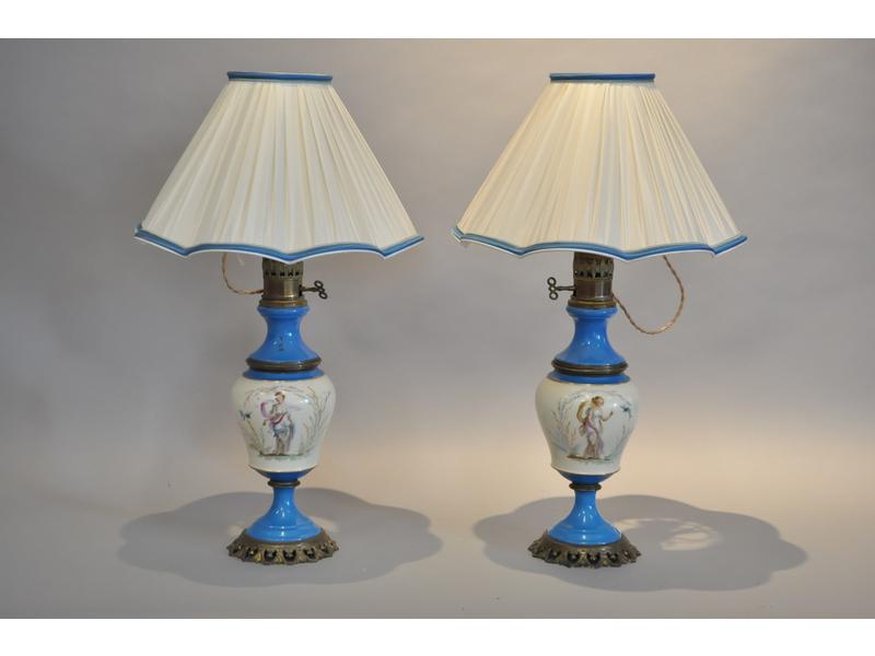 Paire de lampes à pétrole en porcelaine dans le goût de Sèvres à décor de personnages polychromes. Monture en bronze. Fin XIX° siècle. Hauteur totale avec abat-jour: 66cm
