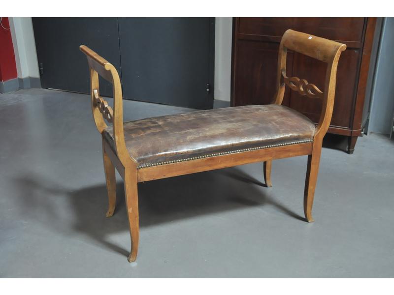 Banquette à chevets inversés en bois naturel, assise recouverte de cuir cloûté.