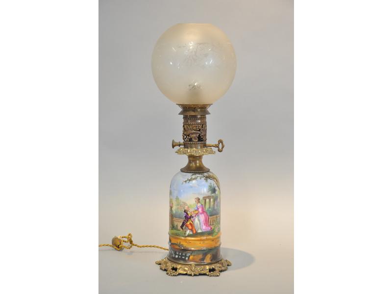 Lampe à pétrole en laiton, réservoir en porcelaine à décor peint d'une scène galante dans un paysage.  Epoque XIXe siècle.  Hauteur totale : 50 cm.