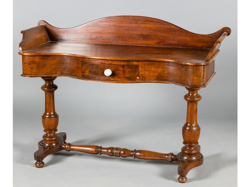 Coiffeuse de style anglais en bois naturel.  Plateau à bords mouvementés ouvrant par un tiroir en ceinture et reposant sur deux pieds balustres reliés par une entretoise.  XXe siècle.  Dim.: 86x120x47 cm.