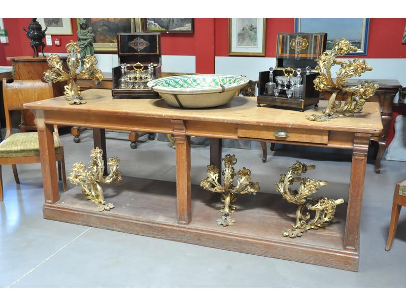 Table de métier en chêne naturel ouvrant par deux tiroirs de part et d'autre en ceinture et reposant sur six pieds gaine moulurés réunis sur un socle à plinthe.  Fin XIXe siècle.  Dim.: 85x225x83 cm. (petits accidents)