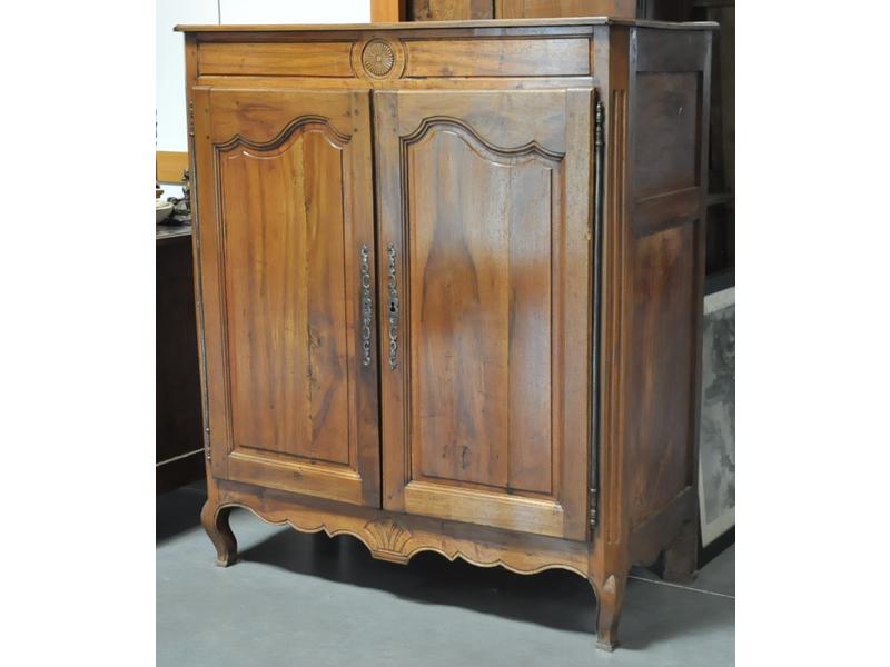 Buffet à hauteur d'appui en noyer ouvrant par deux portes moulurées.  Linteau et traverse sculptés d'une rosace et d'un éventail.  Travail rustique.  Début XIXe siècle.  Dim.: 146x128x58 cm. (plateau vermoulu)
