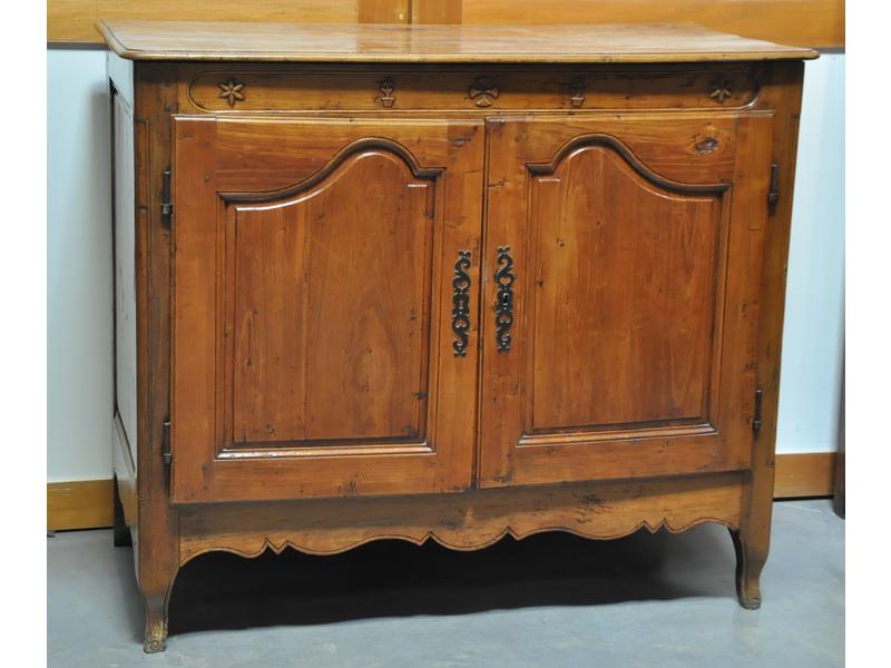 Buffet bas en noyer ouvrant par deux portes et reposant sur un piètement cambré.  Traverse à décor sculpté de motifs géométriques.  Fin XVIIIe début XIXe siècle.  Dim.: 102x120x58 cm.