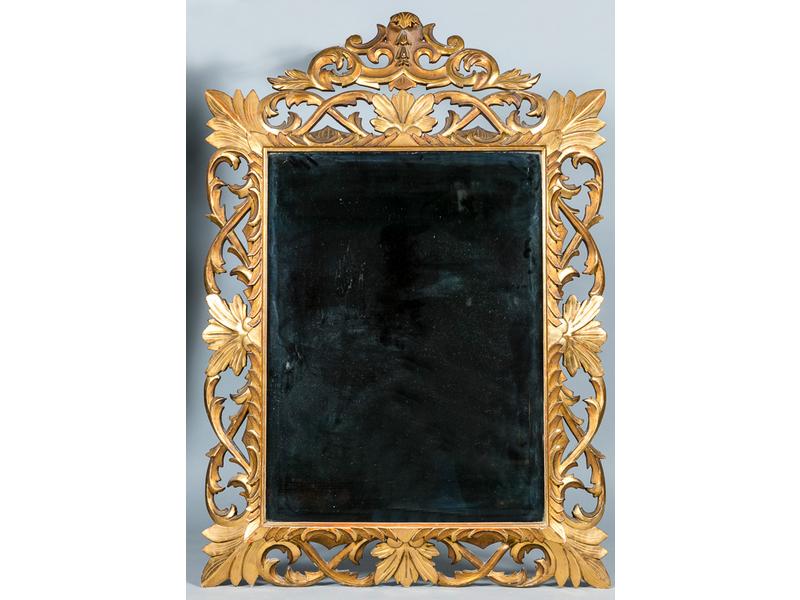Miroir de forme rectangulaire biseauté dans un encadrement à fronton en bois ajouré, sculpté et doré de rinceaux feuillagés. Dim. : 133 x 91 cm.