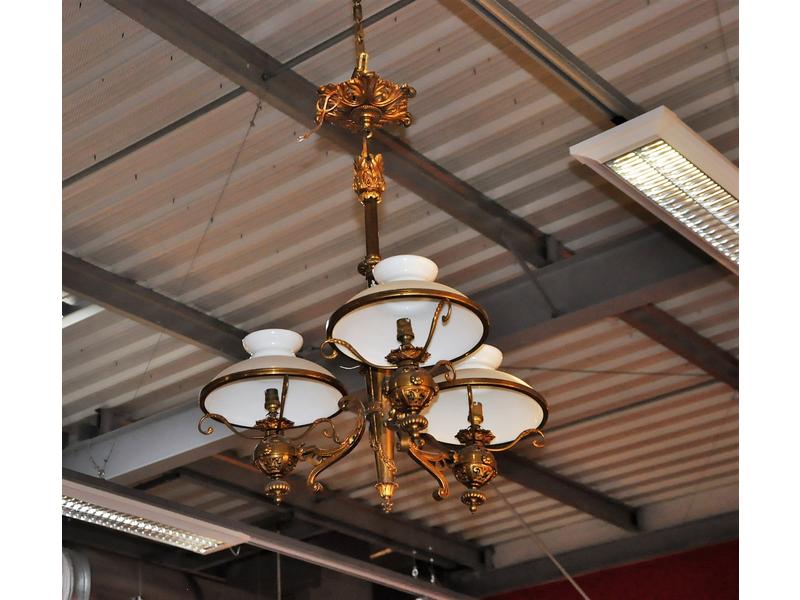 Suspension en laiton éclairant à trois bras de lumière surmontés de trois globes en verre opalin blanc.  Hauteur : 90 cm. (un bras à ressouder)