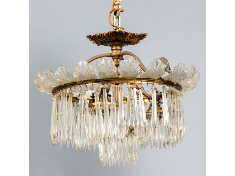 BACCARAT (attribué à) : Petit lustre en métal et bronze éclairant par quatre lumières ornées de pampilles de cristal.  Monture cerclée de feuillages en cristal moulé.  Diamètre : 43 cm.  Hauteur : 35 cm. (quelques manques de pampilles)