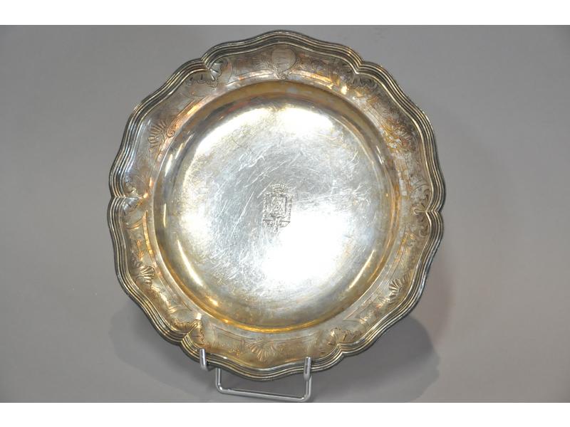 Joli plat en argent en bord en accolade à filets.  Décor ciselé d'un blason au centre et de rocaille sur l'aile.  Poinçons fermiers généraux.  Epoque XVIIIe siècle.  Diam.: 25.5 cm.  Poids : 568g.