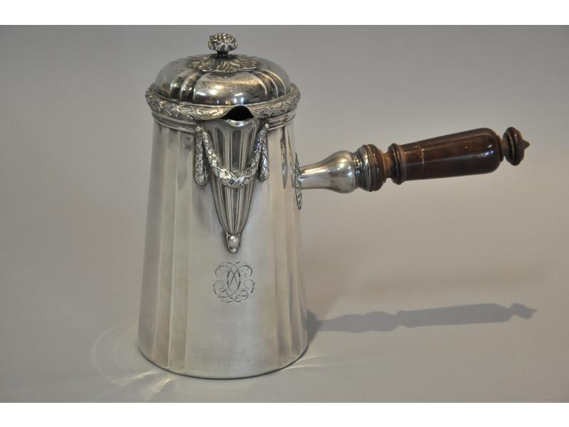 Verseuse en argent de style Louis XVI, panse à cannelures à décor chiffré, le bec verseur orné d'une guirlande de feuilles de lauriers ciselée ainsi que le pourtour du couvercle.  Prise de main en forme de fruit.  Manche en bois tourné.  Poinçon Minerve.  Maître orfèvre : Boin Taburet à Paris.  Poid