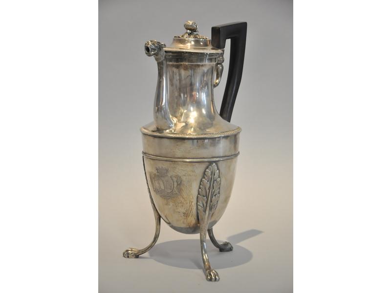 Cafetière en argent de forme balustre reposant sur trois pieds griffes feuillagés. Bec verseur à tête de lion. Couvercle orné d'un fretel à décor de bouton de roses et corps ciselé aux armoiries de Benoist de LAUMONT. Manche en ébène. Paris 1798-1809. (Deux petits chocs). Hauteur : 33 cm.  Poids bru