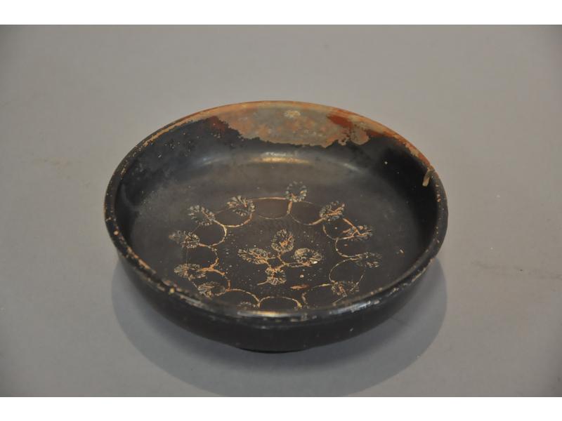 Petite coupelle sur pied antique région de Carthage en terre cuite à engobe noir, le bassin ciselé de fleurs stylisées. (Usures à l'engobe et éclat). Diam.: 13,5cmx45cm