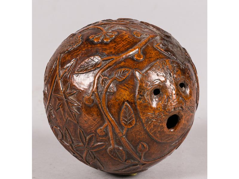 Noix de coco formant boîte à poudre sculptée à décor d'une tête d'animal et branches fleuries.  Début XIXe siècle.  Hauteur : 13 cm.