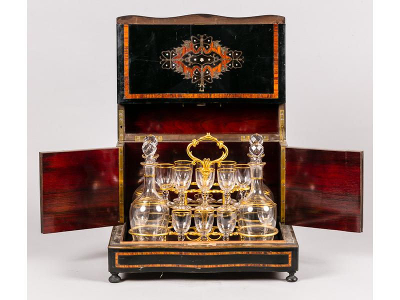 Cave à liqueur en bois noirci marqeuté de bois de rose, de laiton et de nacre.  Intérieur composé de quatre flacons en verre doré et quatorze verres (manquent deux).  Epoque Napoléon III.