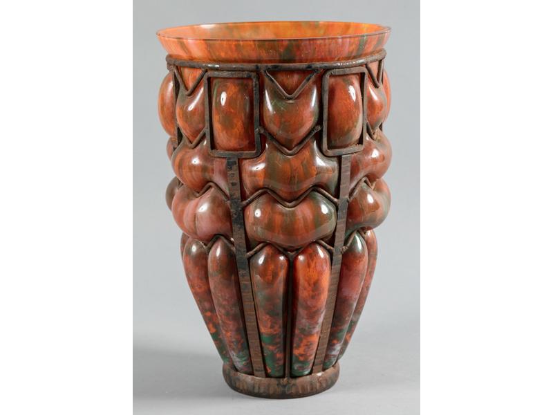 Grand vase en verre soufflé marmoréen orange et vert dans une monture en fer forgé. Vers 1920. (Percé, fêles, petits éclats au col). H.: 41,5cm. Diam.: 26,5cm