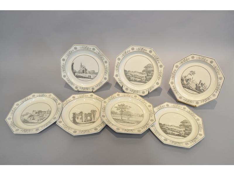 CREIL : Suite de sept assiettes en faïence fine de forme octogonale à décor imrimé en grisaille de paysages anglais, italiens et français. Epoque début XIXe siècle (quelques éclats et usures). Imprimé chez Stone, Coquerel et Le Gros. Diamètre: 23 cm.