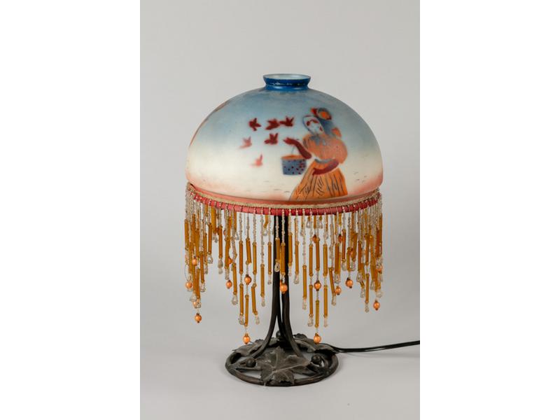 Lampe champignon, abat-jour en verre à décor de femme et oiseaux.  Socle en fer forgé à décor de feuillages.  Epoque 1930.  Hauteur : 38 cm.