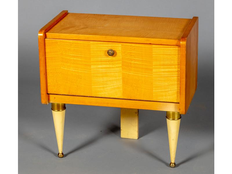 Table de chevet en placage de sycomore ouvrant par un abattant en façade et reposant sur deux pieds antérieurs fuselés, laqués et ornés d'une bague en laiton.  Vers 1940.  Dim.: 52x54x31 cm.