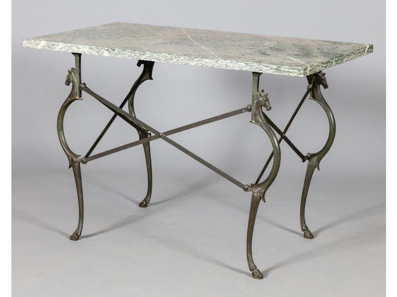 Table de forme rectangulaire, plateau de marbre reposant sur un joli piètement en métal patiné vert antique à motif de têtes et sabots de cheval.  XXe siècle.  Dim.: 75x110x60 cm. (un pied avec une fissure)
