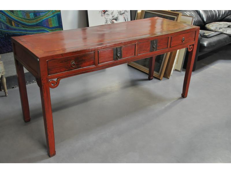 Console chinoise en bois laqué rouge de forme rectangulaire ouvrant par quatre tiroirs en ceinture.  Dim.: 81x165x59.5 cm.