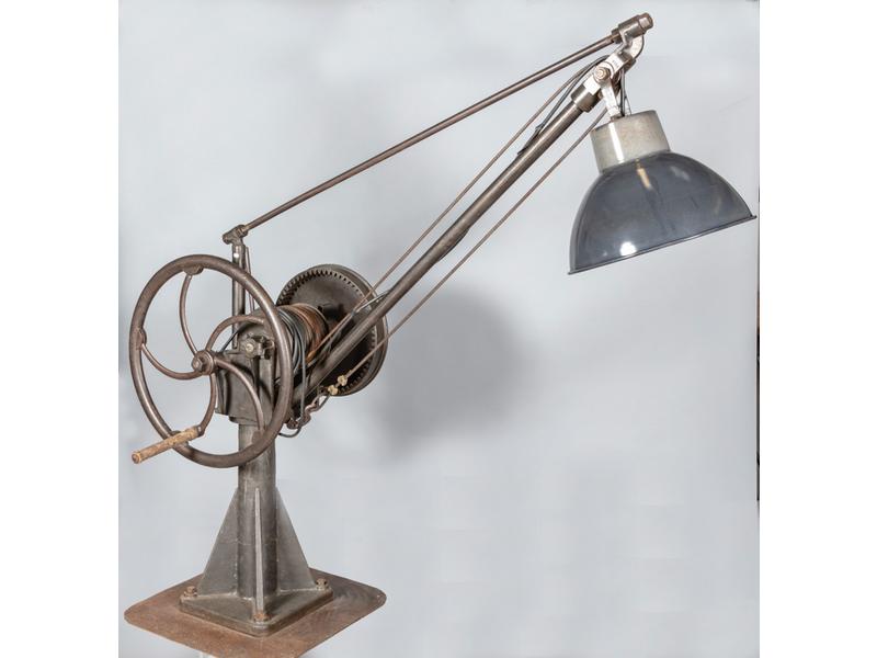 Important lampadaire en fonte construit à partir d'un ancien rouage.  Abat-jour en tôle laqué gris.  Hauteur : 196 cm.