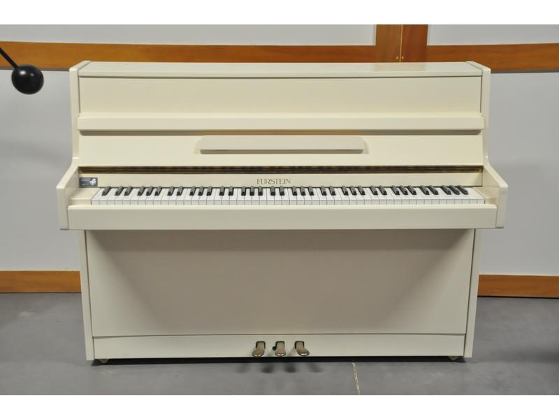 FURSTEIN : Piano droit en bois laqué blanc, cadre en bronze.  Fabrication italienne.  Dim.: 106x138x51 cm.