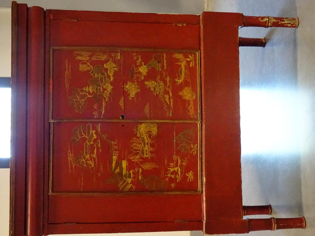CHINE: Petit cabinet en bois laqué rouge ouvrant par deux portes à décor de paysage aux pagodes et reposant sur quatre pieds en forme de bambou. Intérieur ouvrant par dix tiroirs sur cinq rangs. Epoque XX° siècle (fentes et sauts de laque). Dim: 111x88x41cm.