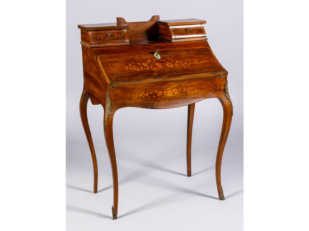 Petit bureau de dame à abattant de style Louis XV en placage de palissandre et à décor marqueté de bouquets de fleurs. Il ouvre par deux  tiroirs à gradin et un abattant formant pupitre découvrant trois petits tiroirs et un compartiment. (sauts de placage). Dim : 101x69.5x47 cm.
