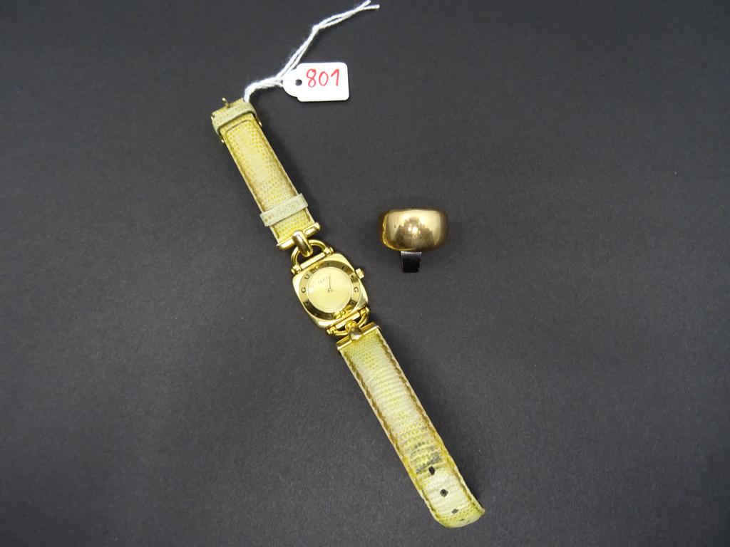 GUCCI : Montre de dame en métal doré, boitier carré, attaches éperons, bracelet cuir (usé) . Mouvement à quartz. Ne fonctionne pas. On joint une bague en métal doré