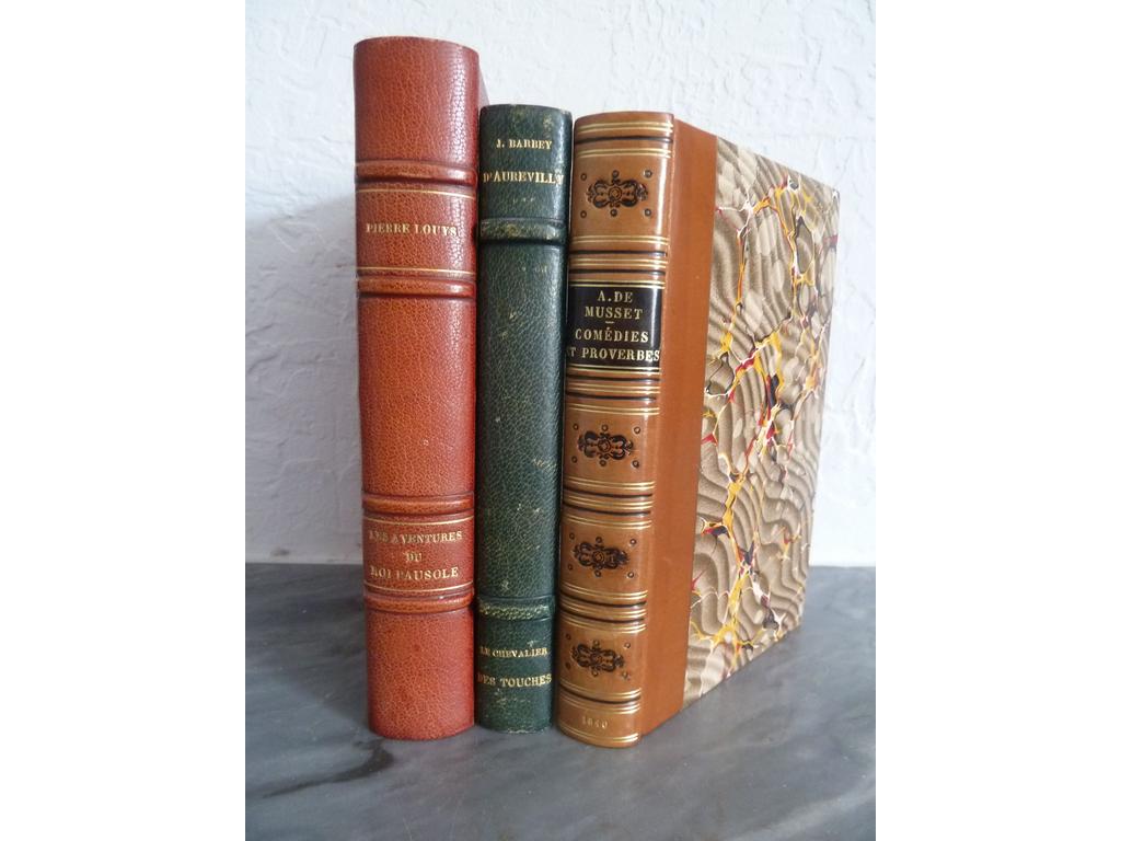 MUSSET, Alfred de : Comédies et proverbes. Paris : Charpentier, 1840. Un volume n-12°,. Reliure 1ère moitié du XXe pastiche du XIXe, demi-veau blond, dos lisse orné de double filet doré et de filets à froid en place des nerfs, fleurons romantiques à froid, pièce de titre en maroquin noir, date dorée en queue, couvertures imprimées conservées. PREMIERE EDITION COLLECTIVE, EN PARTIE ORIGINALE, du théâtre de Musset, dans laquelle : - La Quenouille de Barberine , - Le Chandelier , - Il ne faut jurer de rien et Un caprice paraissent pour la première fois. Les autres pièces figuraient déjà dans Un spectacle dans un fauteuil. Exemplaire lavé ? Ex-libris doré sur pièce de maroquin rouge de Georges DEGRYSE. TRES BEL EXEMPLAIRE. ON Y JOINT : BARBEY dAUREVILLY : Le chevalier des touches. Paris , Lemerre, s.d. Grand in-12°. Reliure demi-maroquin. Illustrations de Buhot et Mittis. ON Y JOINT : LOUYS, Pierre : Les aventures du Roi Pausole. Paris : Piazza, 1939. Reliure demi-maroquin rouge à coins signée par Coulon. Illustrations de Jacques Touchet.