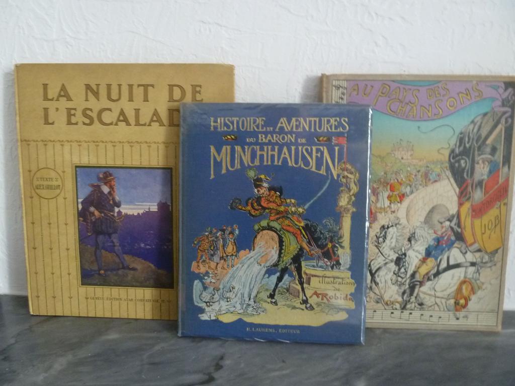 ENSEMBLE DE 3 enfantina dont : -  ROBIDA, Albert : Histoire et aventures du Baron de Munchhausen. Paris : Laurens, 193. Un volume petit in-4°. Reliure de léditeur pleine toile illustrée. Illustrations dAlbert ROBIDA. , - JOB et MONTORGUEIL : Au pays de chansons. Paris : Boivin, s.d. Un volume in-4° sous reliure pleine percaline de léditeur illustrée. (Exemplaire déboité) , - GUILLOT, Alex. (ELZINGRE, Ed.) : La nuit de lescalade. Genève : Atar, 1915. 1 volume grand in-4° sous reliure cartonnée illustrée de léditeur.