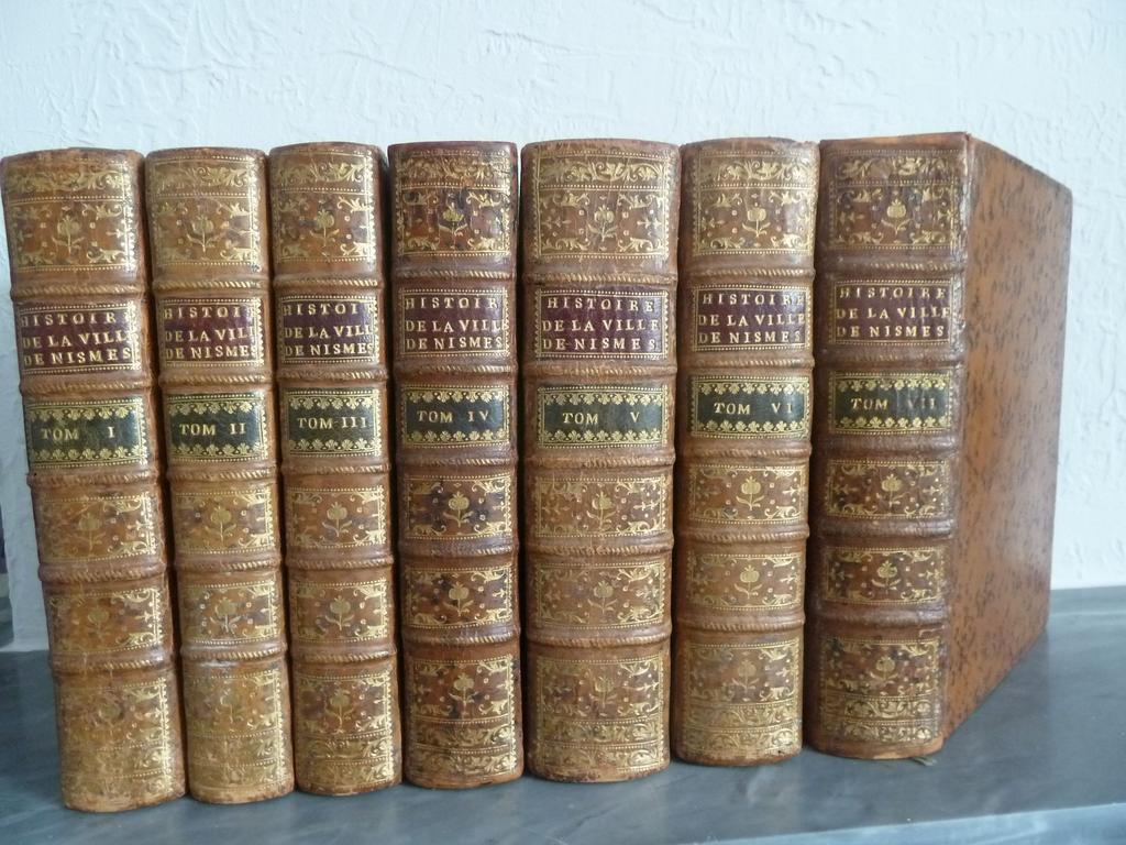 MENARD : Histoire civile, ecclésiastique et littéraire de la ville de Nismes. Paris : Chaubert, 1750-1758. 7 volumes in-4°. Reliures de lépoque plein veau havane, dos à nerfs orné de caissons de double filet doré fleuronnés, pièces de titre en maroquin grenat et de tomaison en maroquin noir, double filet sur coupes, toutes tranches rouges. EDITION ORIGINALE, illustré pour chaque volume dune vignette gravée sur titre répétée de 6 en-têtes et lettrines ornées, plus  au tome 1, de 2 grandes vues dépliantes en tête, dun grand plan dépliant et de 2 hors-texte , au tome 5 de 3 hors-texte dont 2 dépliants , au tome 6, un plan dépliant  et 48 au tome 7 dont 1 in-texte, 28 dépliantes, 19 hors-texte. Ex-libris armorié de Philippe Laurent de Joubert, amateur dart éclairé, mécène du XVIIe, ancien Trésorier des Etats du Languedoc. Quelques rousseurs, des cahiers brunis, très pâle mouillure sur quelques feuillets du tome 7 sinon TRES BEL EXEMPLAIRE de conservation de cette rare édition originale, bien complète de son 7ième tome qui manque souvent.